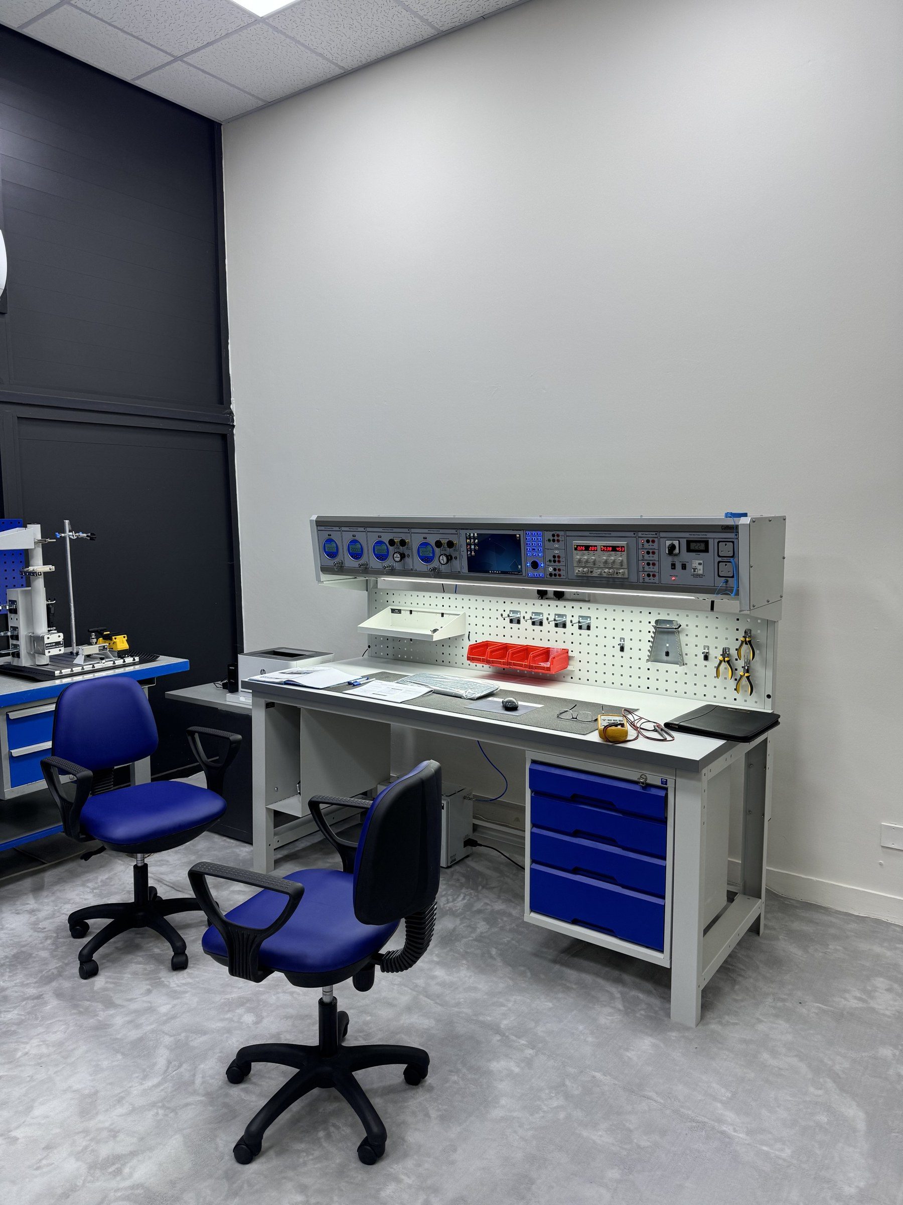 A calibration bench with its chairs and blue drawers.