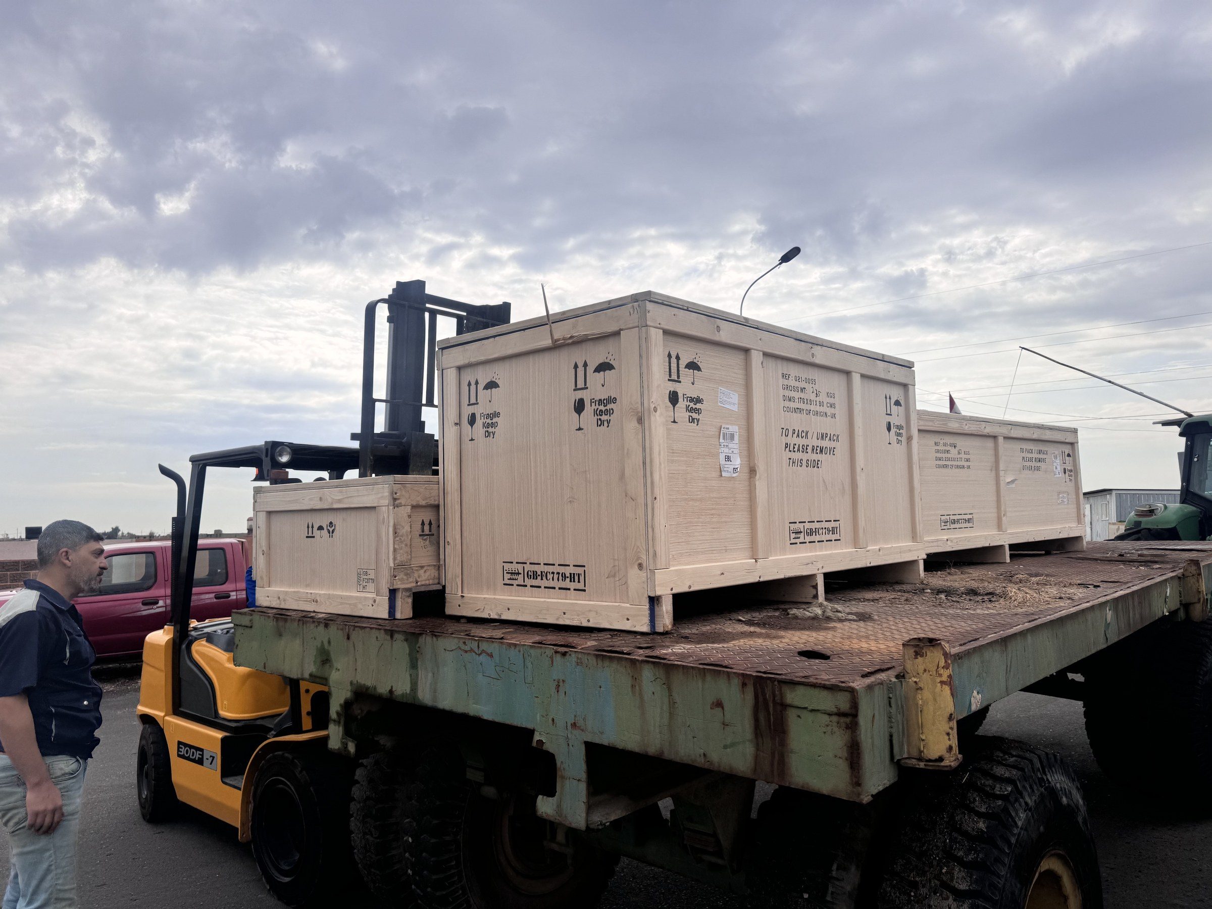 A forklift beside a flatbed trailer carrying the export crates.