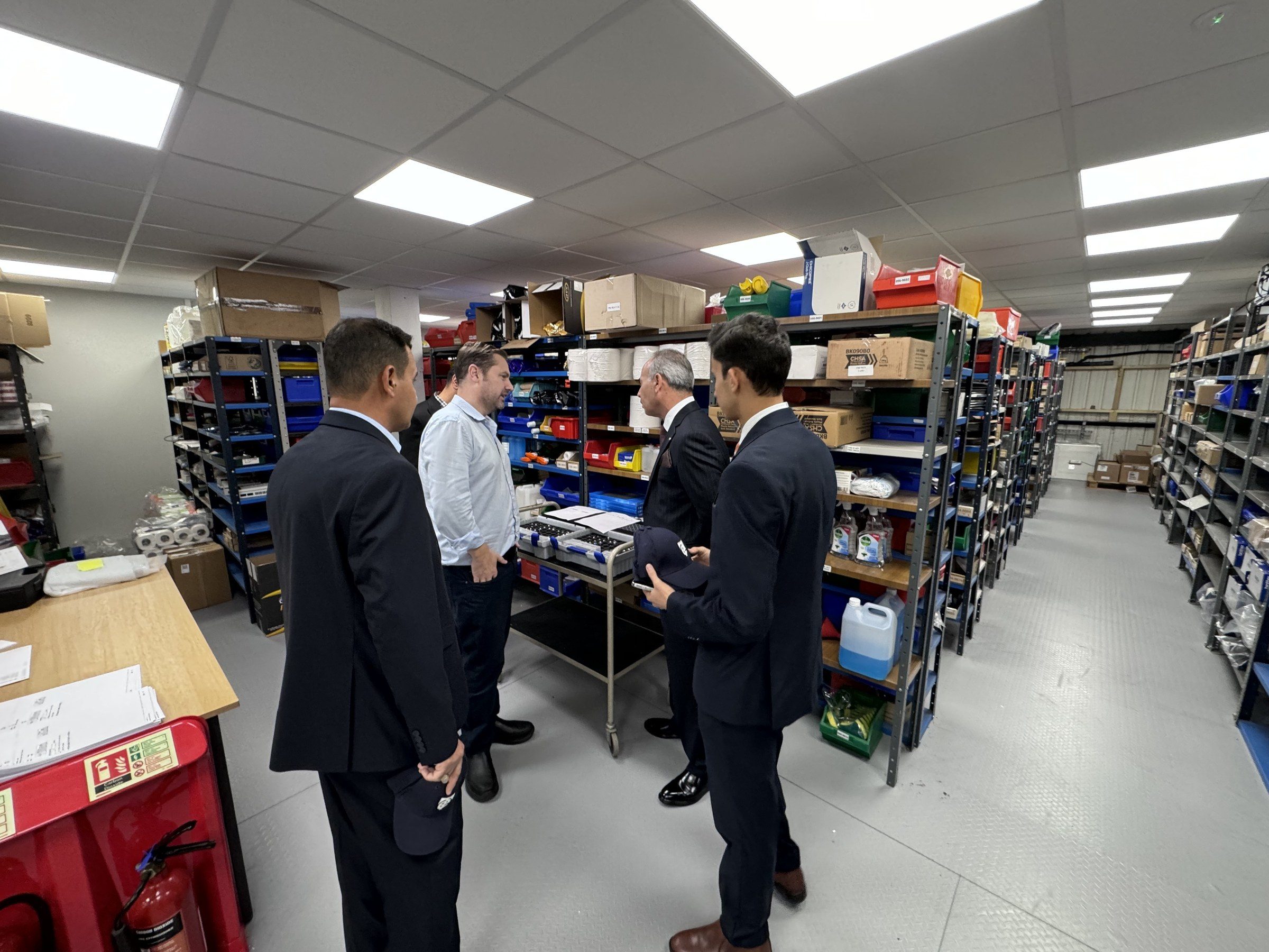 The delegation walking through shelves of parts in the Time Electronics stores.