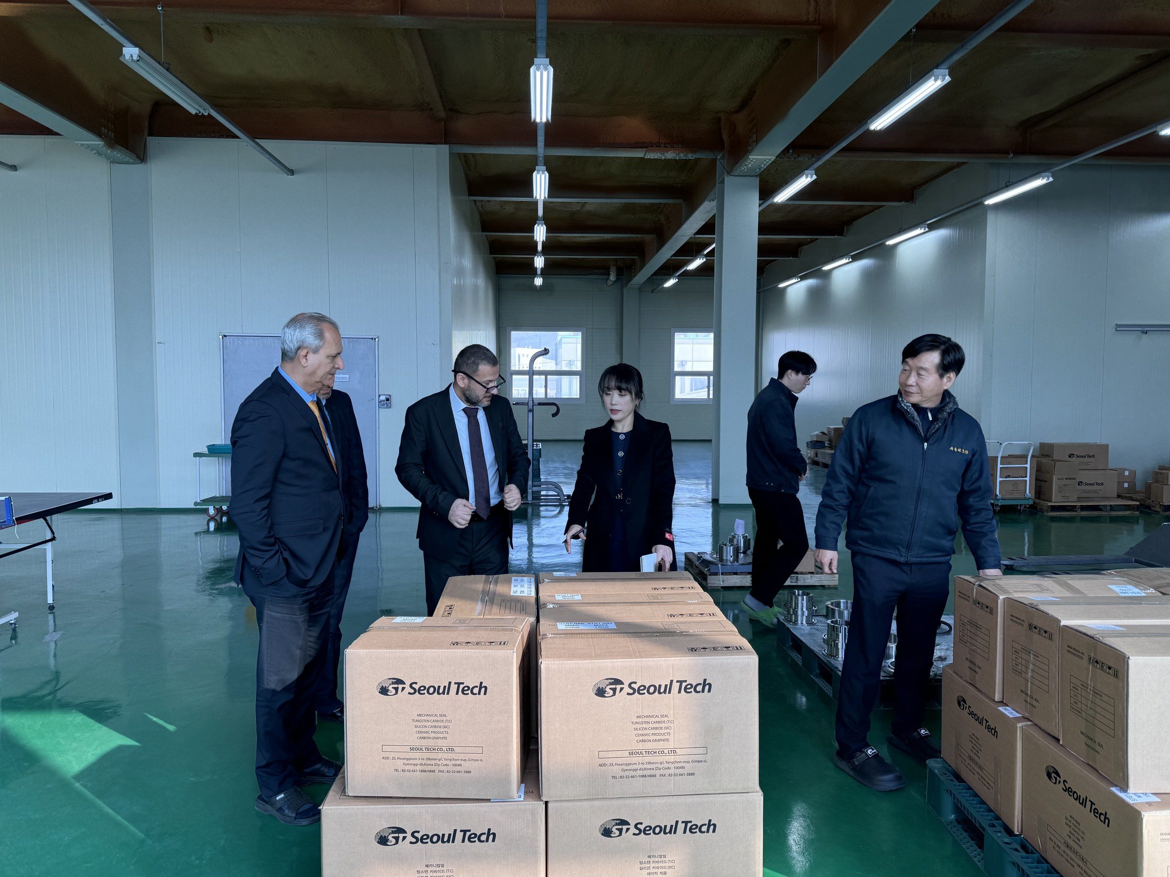 The delegation in the Seoul Tech warehouse beside boxes of mechanical seals.
